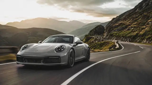 Porsche 911 Carrera T amarillo recorriendo una carretera de montaña al amanecer